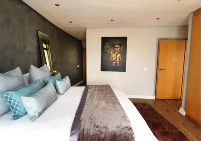 a bedroom with a large bed with blue pillows at Cape Town Sunset Beach Luxury Beachfront Villa in Cape Town