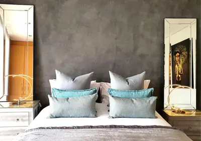 a bedroom with a bed with blue and white pillows at Cape Town Sunset Beach Luxury Beachfront Villa in Cape Town