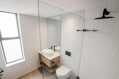 a bathroom with a toilet and a glass shower at Ocean 9 Beachfront Residence in Cape Town