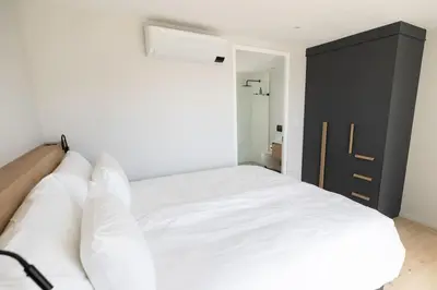 a bedroom with a white bed and a black cabinet at Ocean 9 Beachfront Residence in Cape Town