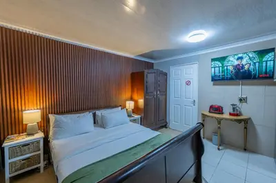 a bedroom with a bed and a wall with a painting at Self Contained 2 bed Room Condo in Parow