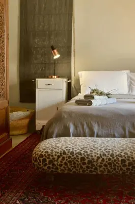 a bedroom with a bed with a stool and a lamp at The Old Dairy at Allemanskloof in Paarl