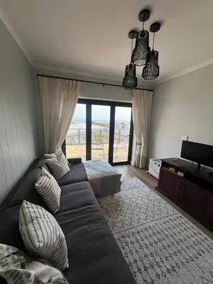 a bedroom with a couch and a bed and a window at Sunset sea views - 4 bedroom home in Hermanus
