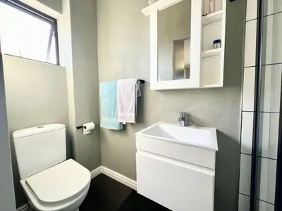 a bathroom with a white toilet and a sink at Cape on Porterfield in Cape Town