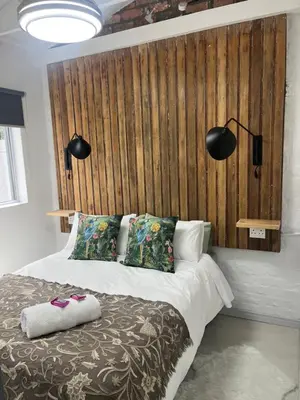 a bedroom with a bed with a wooden headboard at carol close1 small apartment in Eversdal