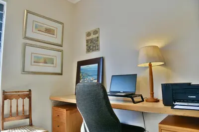 a room with a desk with a laptop and a chair at The Modest Mansion in Cape Town