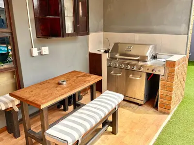 a kitchen with a table and a stove and a wooden table at Hideaway-Poolside Comfort cottage 3km to the Beach in Cape Town