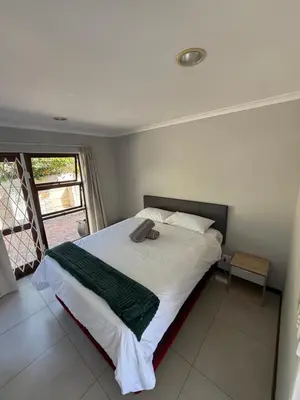 a bedroom with a bed with a book on it at Hideaway-Poolside Comfort cottage 3km to the Beach in Cape Town