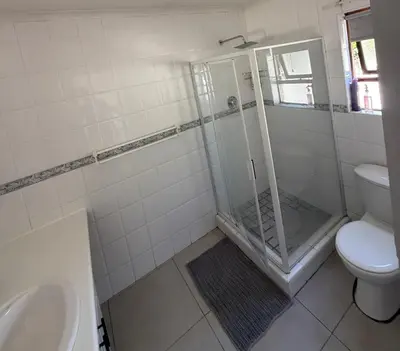 a bathroom with a shower and a toilet and a sink at Hideaway-Poolside Comfort cottage 3km to the Beach in Cape Town