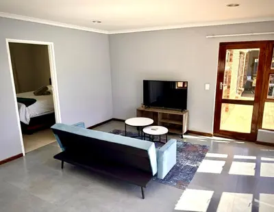 a living room with a couch and a tv at Hideaway-Poolside Comfort cottage 3km to the Beach in Cape Town