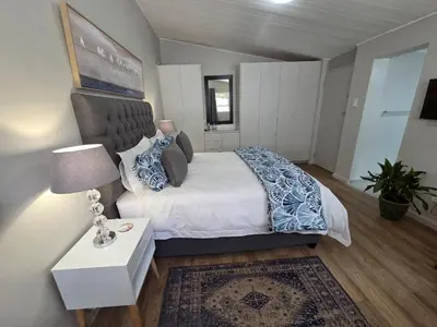 a bedroom with a bed and a table and a lamp at SleepINN at Dumont in Paarl