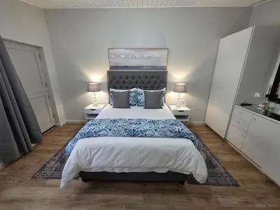 a bedroom with a large bed and two lamps at SleepINN at Dumont in Paarl