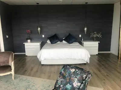 a bedroom with a white bed and a black wall at Luxury Family Home in Helderberg