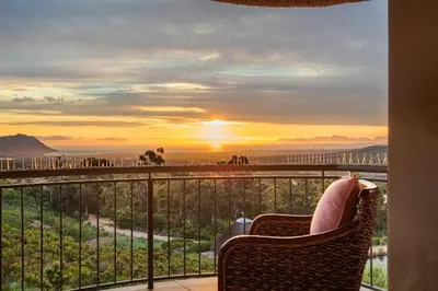 a person sitting in a chair on a balcony watching the sunset at Villa Bezweni in Somerset West