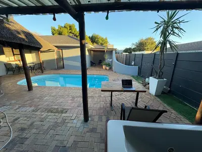 a patio with a table and a swimming pool at Joy House in Cape Town