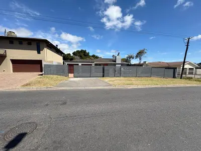 an empty street in front of a house with a fence at Joy House in Cape Town