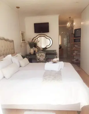 a bedroom with a large white bed with a tv on the wall at LaPlace in Strand