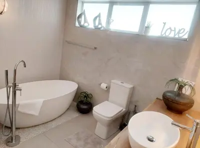 a bathroom with a tub and a toilet and a sink at LaPlace in Strand