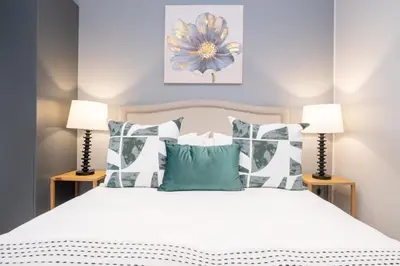a bedroom with a white bed with two lamps at 410 Riverlands - Lux 1 bedroom Apartment in Cape Town