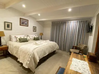 a bedroom with a large white bed and a table at Skurwejantjie in Hermanus