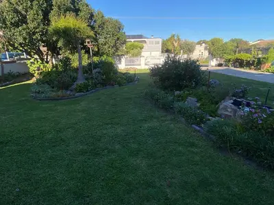 a yard with flowers and plants in the grass at Skurwejantjie in Hermanus