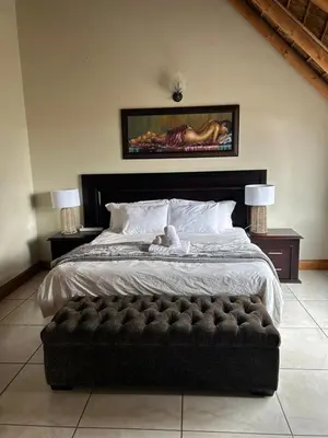 a bedroom with a large bed with a black ottoman at Daisy Accomodation and Spa 5 Bed all private en-suite in Cape Town