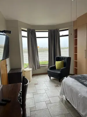 a bedroom with a bed and a chair and windows at Daisy Accomodation and Spa 5 Bed all private en-suite in Cape Town