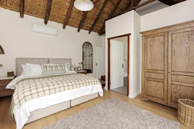 a bedroom with a bed and a large wooden cabinet at Villa Canetsfontein in Wellington