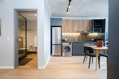 a kitchen and dining room with a table and a refrigerator at 714 Riverlands - Lux Studio Apartment in Cape Town
