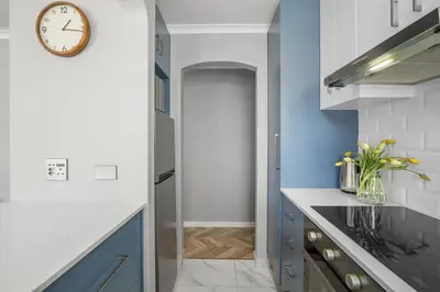 a kitchen with blue cabinets and a clock on the wall at 17 Megans Place in Bloubergstrand