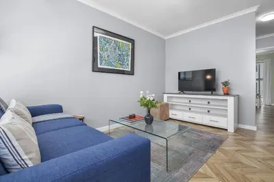 a living room with a blue couch and a tv at 17 Megans Place in Bloubergstrand