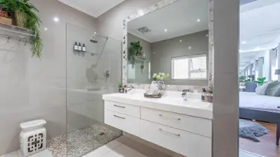 a white bathroom with a sink and a shower at Sunsets' Engina Villa, Sunset Beach in Cape Town