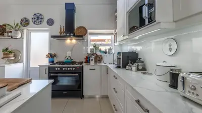 a kitchen with white counters and a black stove top oven at Sunsets' Engina Villa, Sunset Beach in Cape Town