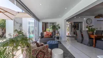a living room with couches and a table at Sunsets' Engina Villa, Sunset Beach in Cape Town