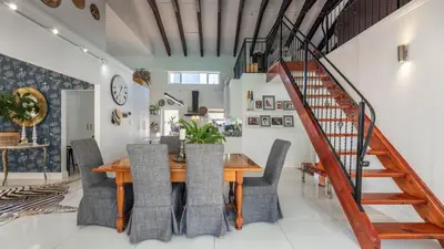 a dining room with a table and chairs and a staircase at Sunsets' Engina Villa, Sunset Beach in Cape Town
