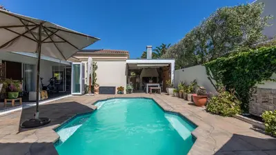 a swimming pool in the backyard of a house at Sunsets' Engina Villa, Sunset Beach in Cape Town