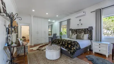 a bedroom with a king sized bed and a desk at Sunsets' Engina Villa, Sunset Beach in Cape Town
