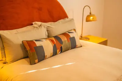 a bed with a pillow on it with a lamp at The Nest Franschhoek in Franschhoek
