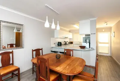 a kitchen and dining room with a wooden table at 706 Odeon Towers - Ocean Splendour in Strand