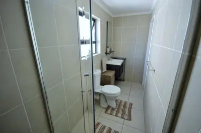 a bathroom with a toilet and a sink at The Sandown - One Bed Apartment with Balcony & Pool View in Cape Town