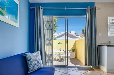 a living room with a blue couch and a sliding glass door at Sea Breeze Kite Dreams 1 in Cape Town