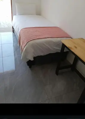 a bedroom with a bed and a wooden table at 60 On Kosmos in Bellville South