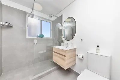 a white bathroom with a sink and a mirror at Beachfront Apt Kite Beach with Table Mtn View Horizon Bay 501 in Cape Town