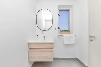 a white bathroom with a mirror and a sink at Beachfront Apt Kite Beach with Table Mtn View Horizon Bay 501 in Cape Town