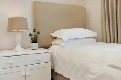 a bedroom with a white bed with a lamp on a dresser at Beachfront Apt Kite Beach with Table Mtn View Horizon Bay 501 in Cape Town