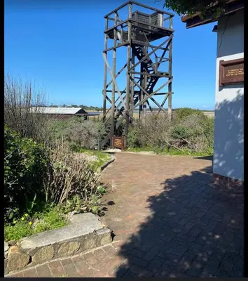 a clock tower sitting next to a building at Birds Nest Holiday Apartment in Zeekoevlei
