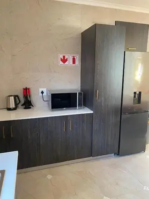 a kitchen with a microwave and a refrigerator at Birds Nest Holiday Apartment in Zeekoevlei