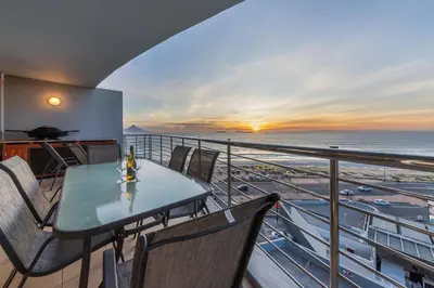 a table and chairs on a balcony with a view of the ocean at Beautiful 3 bed apartment with sea views Horizon Bay 502 in Cape Town