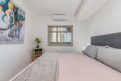 a white bedroom with a large bed and a window at Beautiful 3 bed apartment with sea views Horizon Bay 502 in Cape Town