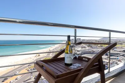 a bottle of wine sitting on a chair on a balcony at Beachfront Bliss with Table Mountain Views Horizon Bay 801 in Cape Town